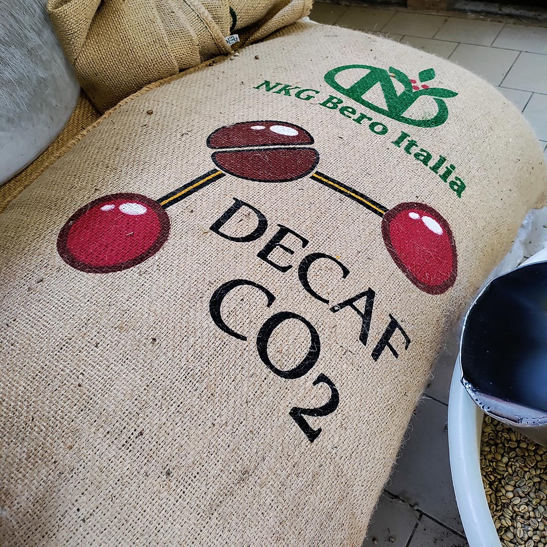 Il sacco di juta con il caffè verde decaffeinato ad acqua e anidrite carbonica (CO<sub>2</sub>) nel nostro locale di stoccaggio del caffè crudo in attesa di essere miscelato e tostato (torrefatto)